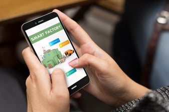 Woman holding mobile device connected to smart factory via the Industrial Internet of Things