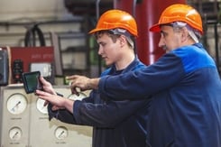 2 manufacturing employees working on a tablet