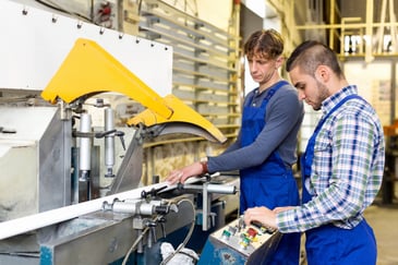 Two millennials working on a machine